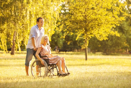 A man helping a woman in a wheelchair outdoors