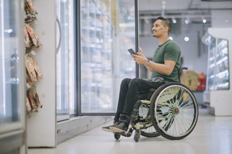 Man in a wheelchair checks a tablet at a grocery store