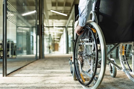 Man in wheelchair rolls through an empty hallway