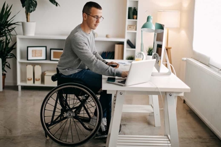 Man in a wheelchair works on a computer at a desk
