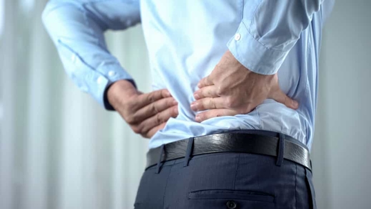 Businessman clutches his lower back in pain