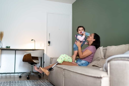 Mother with a prosthetic leg holds her child while sitting on the couch