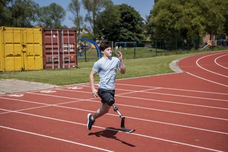 Paraplegic man with a prosthetic leg runs on a track field