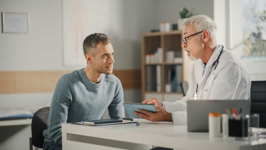 Physician speaks with his patient in an exam room