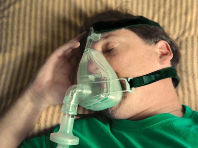 A man is lying down, wearing a breathing mask.