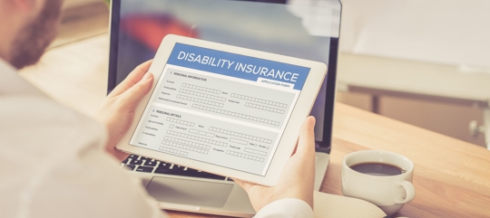 A person is holding a tablet displaying a disability insurance form.