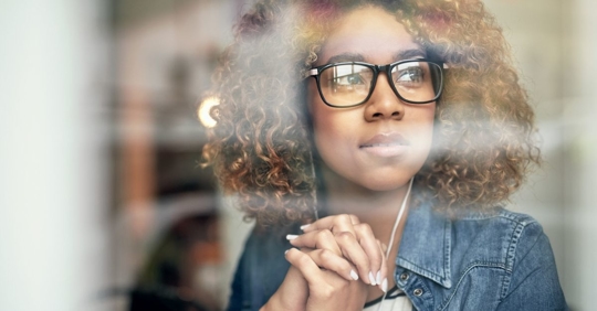Woman looking out window after she filed a long term disability claim.