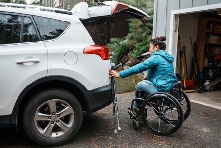 a woman in wheelchair getting into car