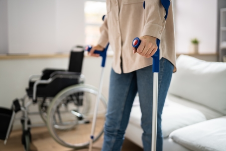 woman with crutches and wheelchair in background