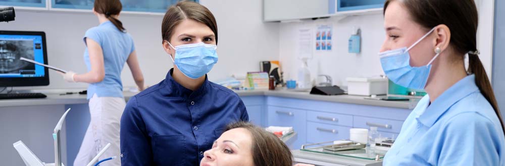Three dental assistants helping a patient.